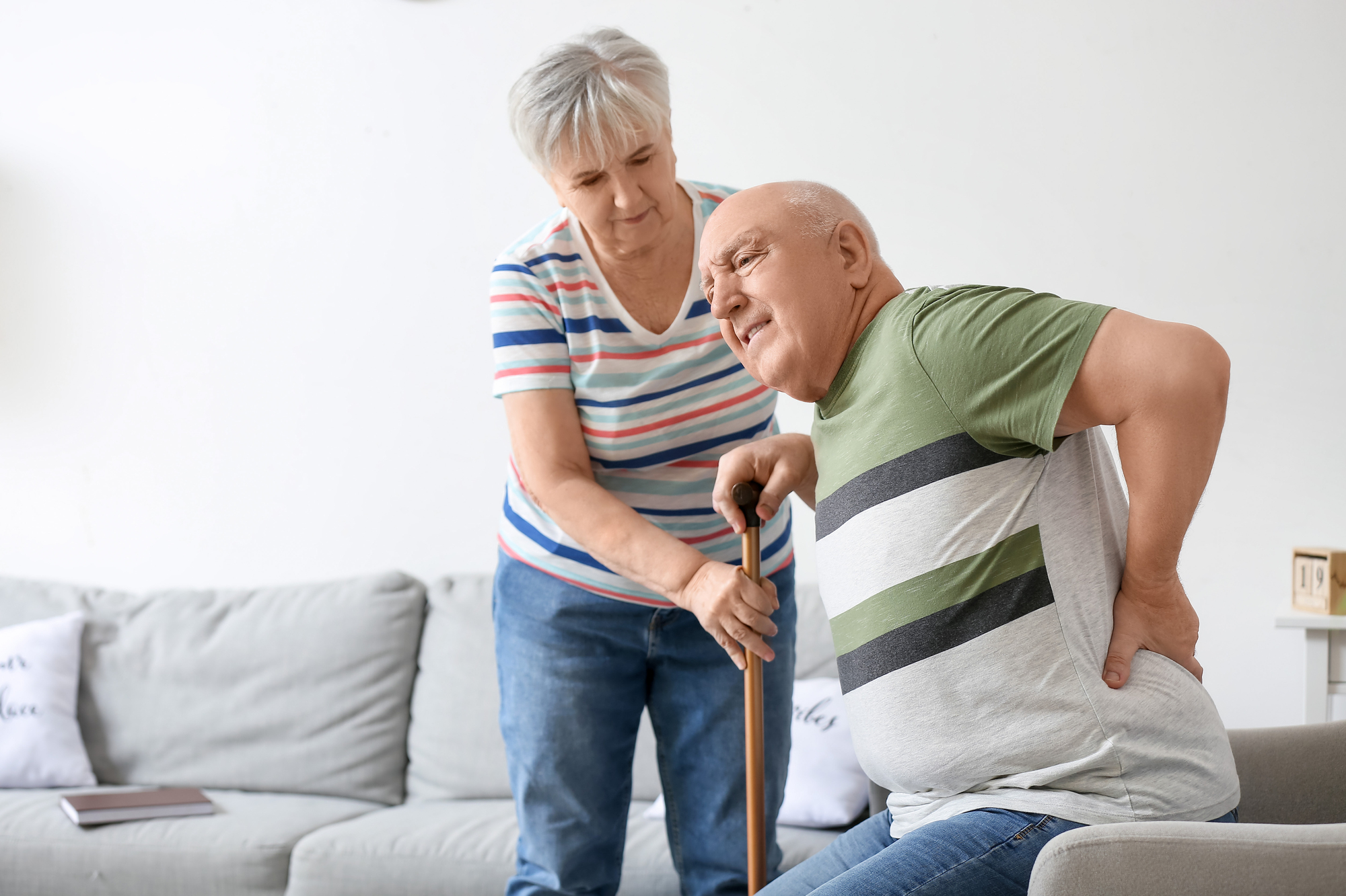 Senior woman helping her husband with back pain at home Senior woman helping her husband with back pain at home